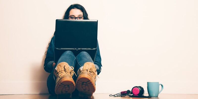 Girl sitting on floor using laptop